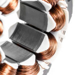 Detail of copper winding, stack and shaft of a  electric permanent magnet motor for home appliances. Selective focus and white background.