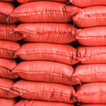 Piles of sacks with agricultural products in storehouse